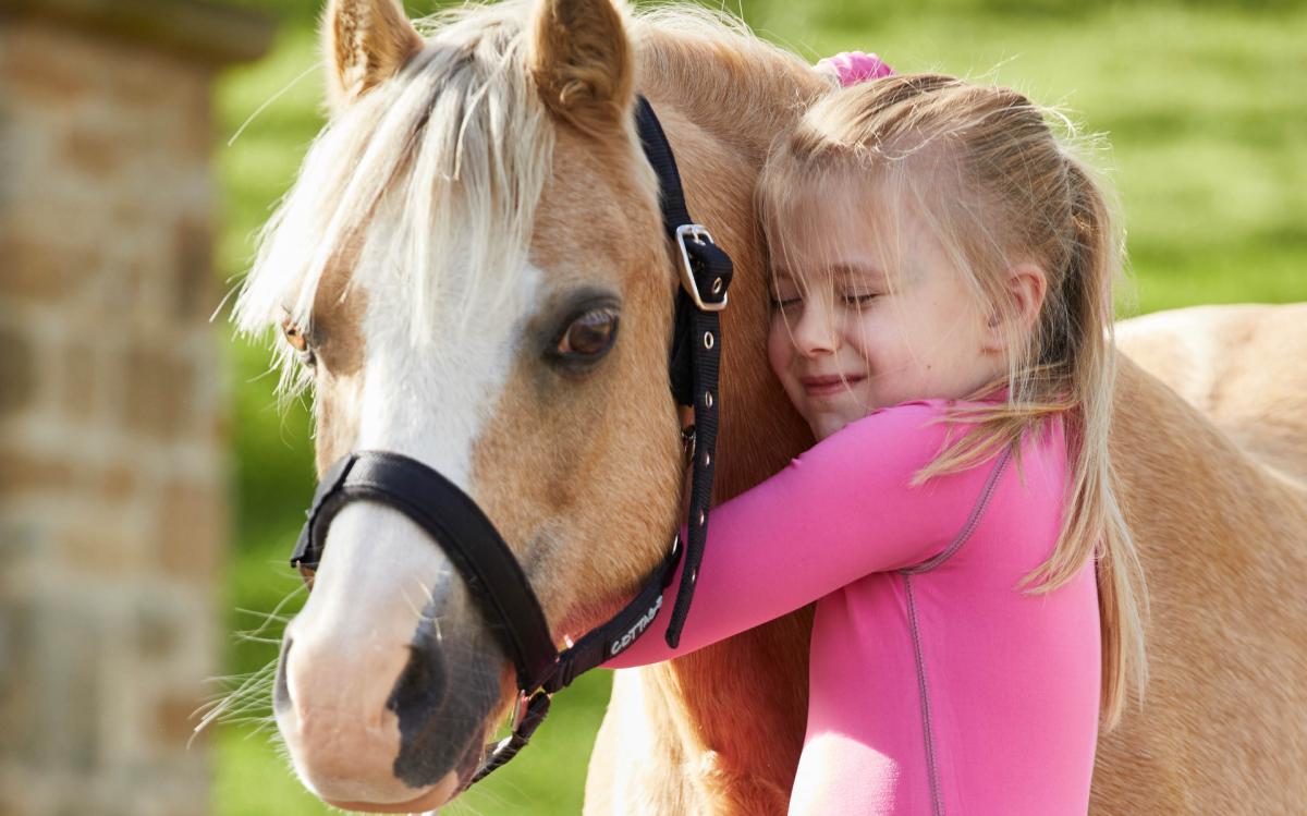 young girl hugging a horse